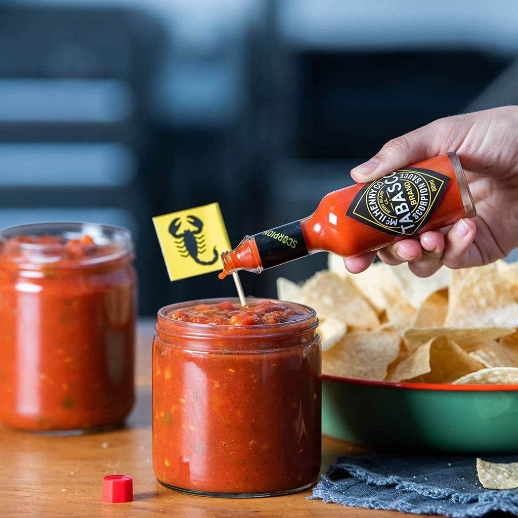 TABASCO® Scorpion Pepper Sauce in a 59ml glass bottle being poured onto some delicious nacho sauce